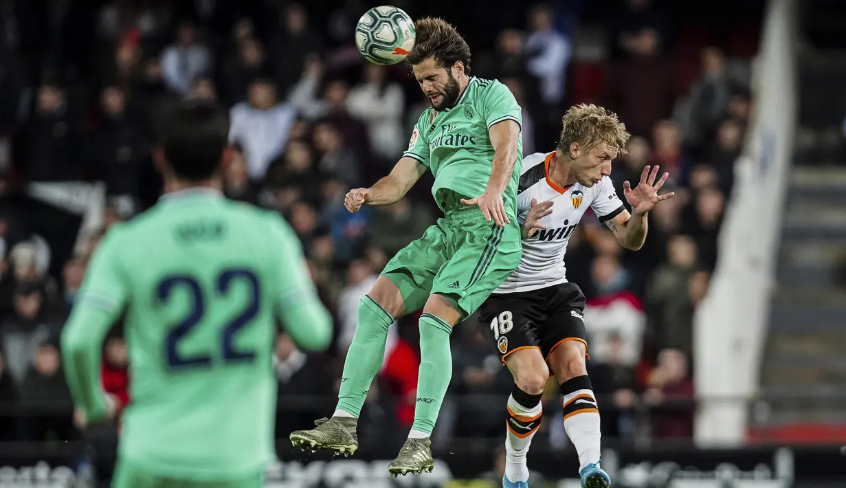 Gelandang Valencia, Daniel Wass berebut bola  udara dengan bek Real Madrid, Nacho pada pertandingan lanjutan La Liga Spanyol di Stadion Mestalla (15/12/2019). Madrid bermain imbang 1-1 atas Valencia. (AP Photo/Alberto Saiz)