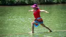 Seorang perempuan melakukan aksi meniti satu bambu di atas air di Chishui, Provinsi Guizhou, China pada 25 Juni 2020. Seni meniti satu bambu berasal dari Guizhou ini mengharuskan seseorang untuk berdiri atau duduk di atas sebatang bambu sembari melakukan gerakan keseimbangan. (Xinhua/Tao Liang)