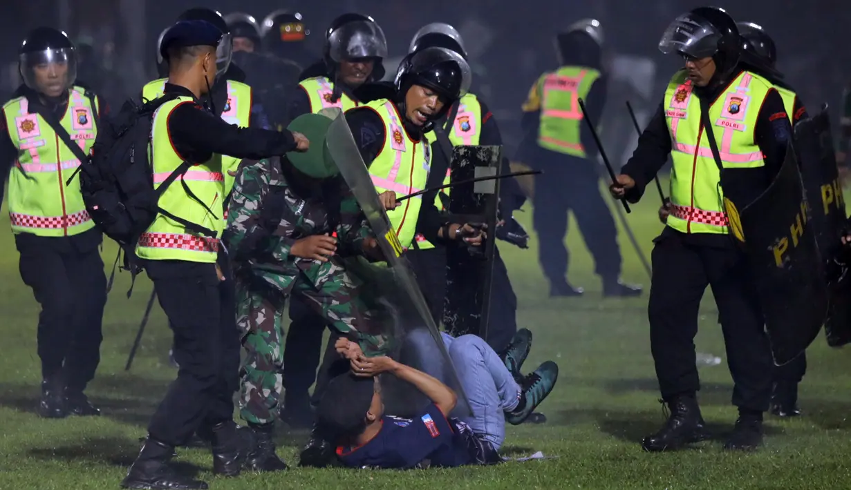 Petugas keamanan menahan seorang suporter saat kerusuhan pada pertandingan sepak bola antara Arema Vs Persebaya di Stadion Kanjuruhan, Malang, Jawa Timur, 1 Oktober 2022. "Dalam kejadian itu, telah meninggal 127 orang, dua di antaranya adalah anggota Polri," kata Kapolda Jawa Timur Irjen Pol Nico Afinta. (AP Photo/Yudha Prabowo)
