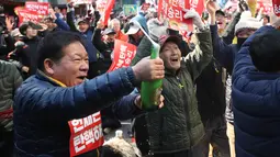 Pengunjuk rasa membuka botol sampanye untuk merayakan pemakzulan Presiden Korea Selatan Park Geun-hye oleh Mahkamah Konstitusi di Seoul, Jumat (10/3). Park Geun-hye dimakzulkan atas skandal korupsi yang melibatkan perusahaan besar. (AP Photo/Lee Jin-man)