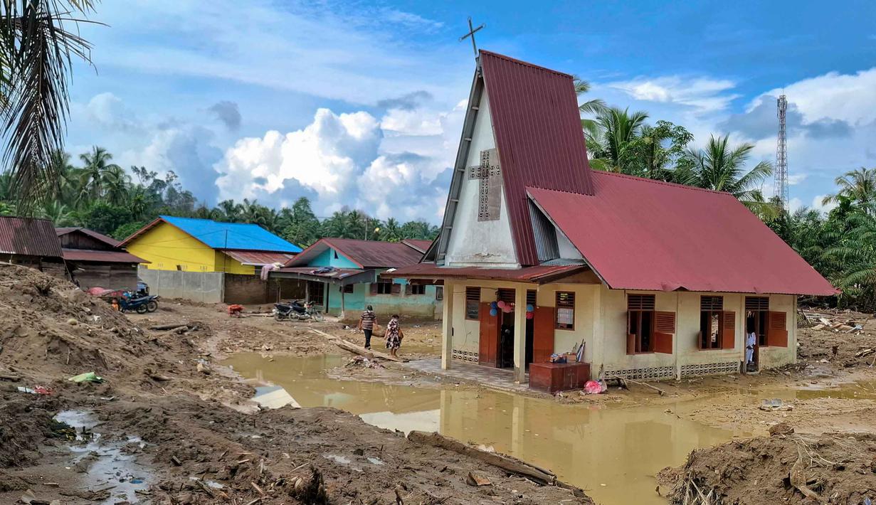 Warga desa berjalan menuju Gereja Protestan Angkola di desa Aek Ngadol, Tapanuli Selatan, Sumatera Utara, pada Kamis 25 Desember 2025, setelah banjir dan tanah longsor yang melanda di daerah tersebut pada akhir November 2025 lalu. Warga desa Aek Ngadol, Tapanuli Selatan, Sumatera Utara, merayakan Natal 2025 dalam suasana penuh keprihatinan. (AMROE/AFP)