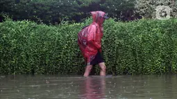 Warga melintasi Jalan Di Panjaitan dekat Halte Transjakarta Cawang Soetoyo yang banjir, Jakarta, Rabu (1/1/2020). Hujan yang mengguyur Jakarta sejak Selasa sore (31/12/2019) mengakibatkan banjir di sejumlah titik di Jakarta. (Liputan6.com/Helmi Fithriansyah)