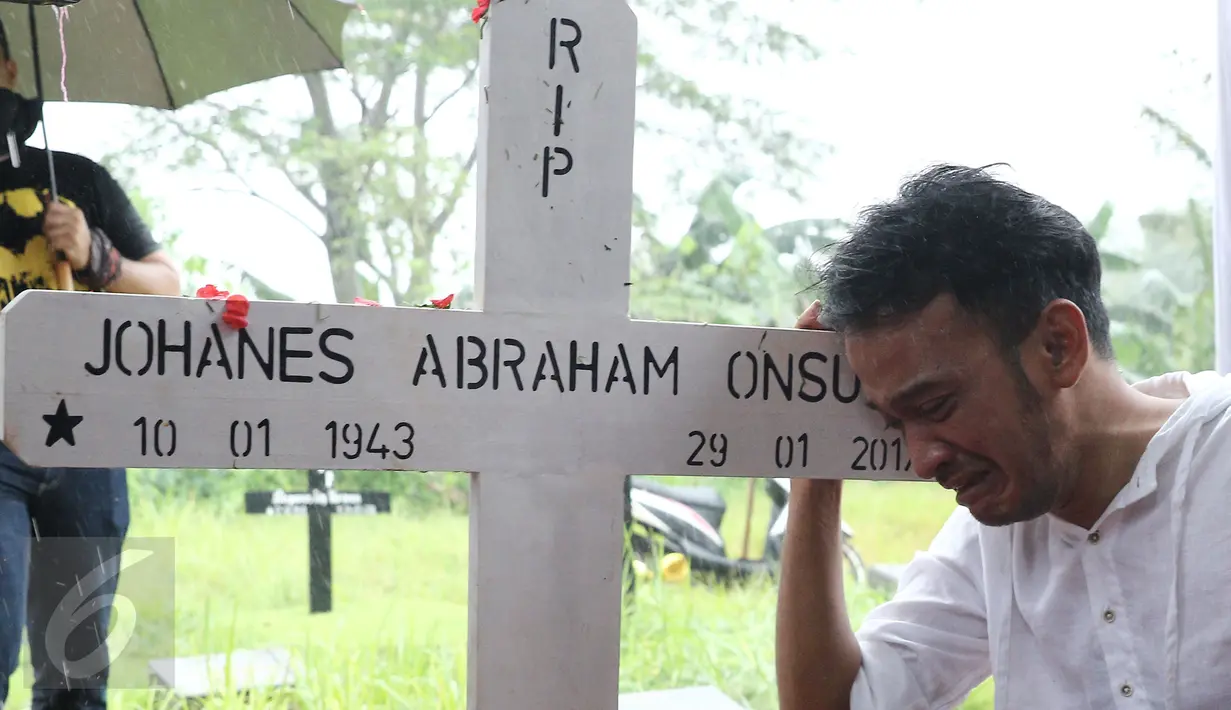 Artis Ruben Onsu menangis sambil memegang kayu nisan sang ayah, Johannes Abraham Onsu di TPU Pondok Ranggon, Jakarta Timur, Rabu (1/2). Ayah Ruben dan Jordi Onsu diketahui sempat mengalami komplikasi penyakit. (Liputan6.com/Herman Zakharia)