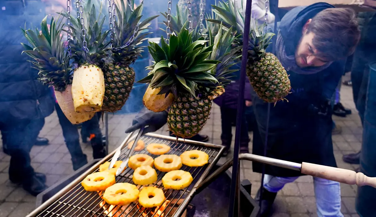 Seorang pria memanggang irisan nanas saat Riga Street Food Festival di Riga, Latvia, Sabtu (18/1/2020). Api unggun dan kios-kios makanan didirikan di sudut Jalan Kalku dan Valnu di Kota Tua Riga agar pengunjung dapat menikmati berbagai hidangan populer dari kota tersebut. (Xinhua/Janis)