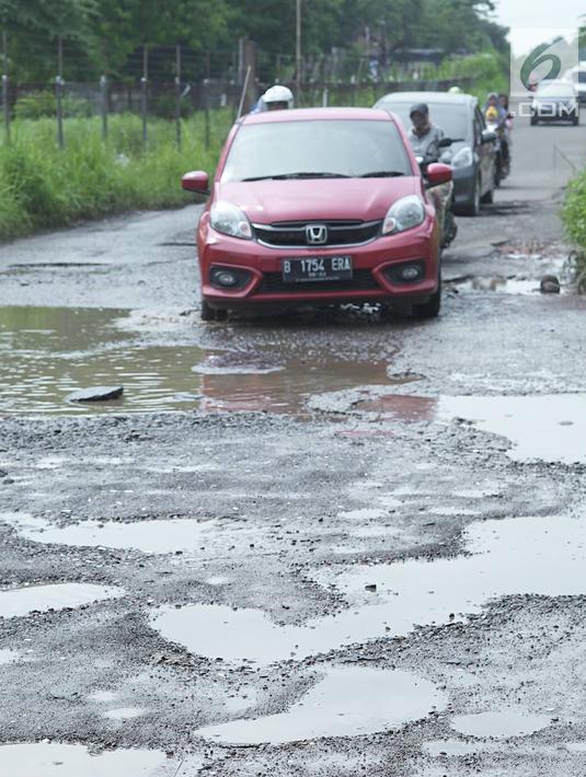 Kendaraan melintasi jalan yang rusak di Jalan Raya Gas Alam, Depok, Jawa Barat, Selasa (7/5). Kondisi jalan yang tidak kunjung diperbaiki tersebut menjadi kubangan air setiap hujan serta berbahaya bagi keselamatan pengguna jalan. (Liputan6.com/Immanuel Antonius)