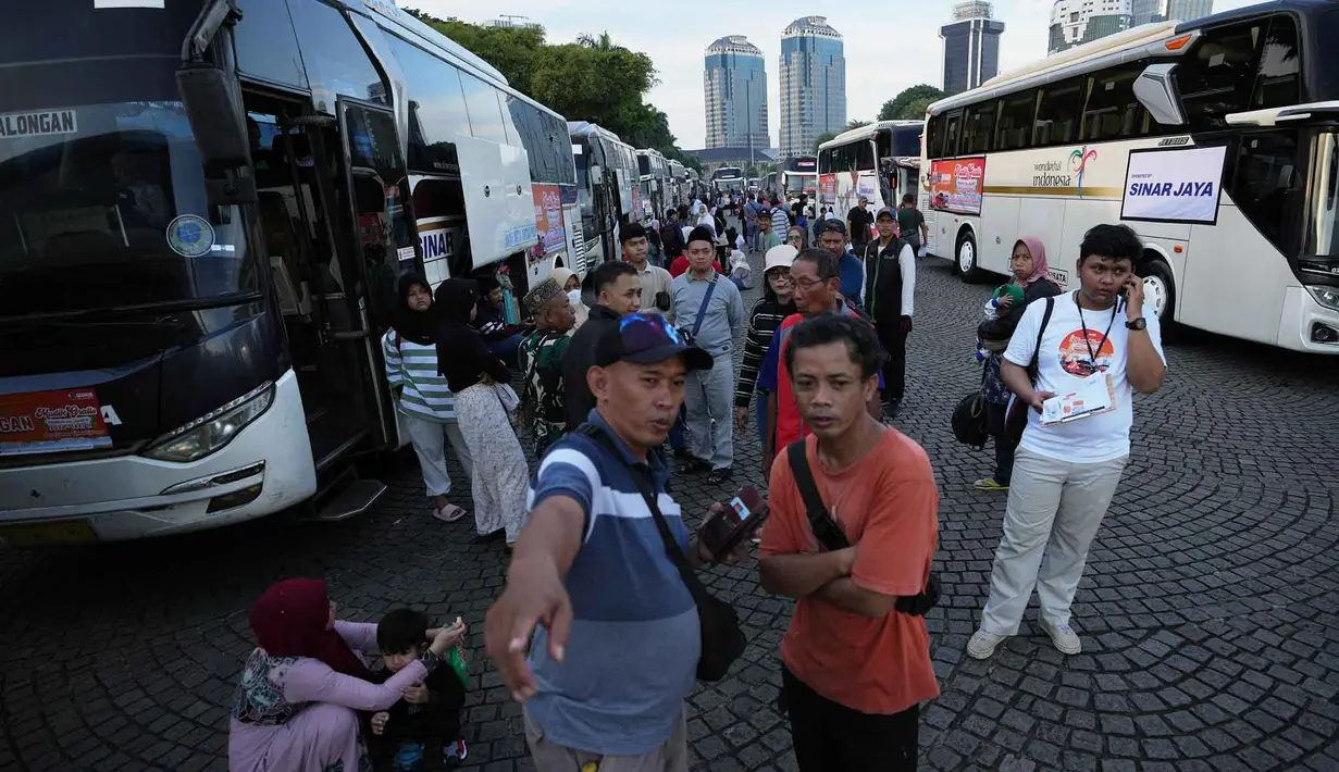 Sebanyak 33.902 pemudik diberangkatkan dalam program tahun ini. Tampak dalam foto, orang-orang menunggu untuk menaiki bus yang akan mengangkut mereka ke kampung halaman untuk merayakan Hari Raya Idul Fitri 1447 Hijriah dalam perjalanan mudik gratis yang diselenggarakan oleh Pemerintah Provinsi Jakarta di Lapangan Monumen Nasional, Selasa 17 Maret 2026. (AP Photo/Achmad Ibrahim)