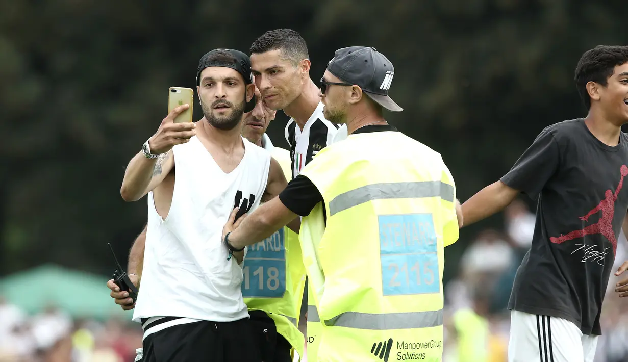 Seorang suporter Juventus berselfie dengan Cristiano Ronaldo selama pertandingan persahabatan antara Juventus A dan tim B, di Villar Perosa, Italia utara, (12/8). Suporter tersebut masuk ke lapangan pada babak pertama. (AP Photo/Antonio Calanni)