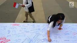 Seorang wanita menandatangani kain putih saat melakukan deklarasi Indonesia Bangkit saat hari kebangktian nasional ke 111 tahun di GBK, Jakarta, Senin (20/5). Tujuan deklarasi ini untuk menyegarkan kembali ingatan dan tekad merawat persatuan Indonesia. (Liputan6.com/Angga Yuniar)