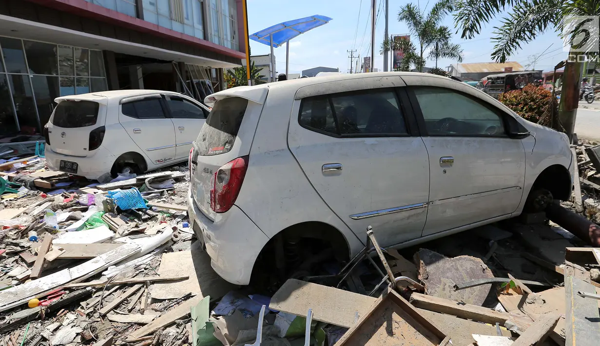 Dua mobil Daihatsu Ayla menjadi incaran jarahan korban gempa dan tsunami di Palu Grand Mal, Palu, Jumat (5/10). Warga korban gempa bumi mengambil ban dan interior mobil. (Liputan6.com/Fery Pradolo)