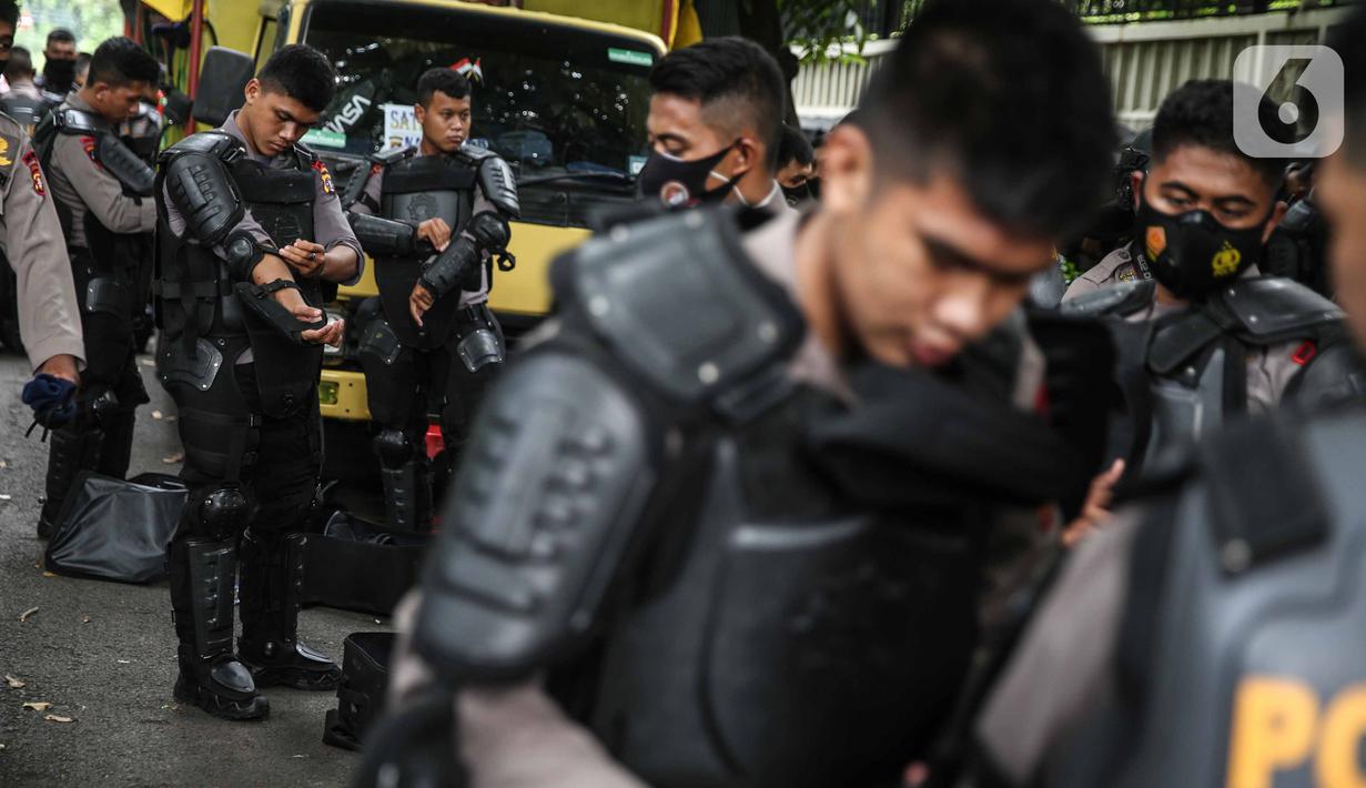 Personel Brimob bersiap mengenakan perlengkapan pelindung diri di Kawasan Bundaran HI, Jakarta, Selasa (13/10/2020). Sebanyak kurang lebih 12 ribu personel gabungan TNI, Polri dan Pemprov DKI Jakarta diterjunkan mengawal aksi tolak Undang-Undang Cipta Kerja Omnibus Law. (Liputan6.com/Faizal Fanani)