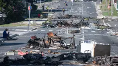Sebuah jalan diblokir oleh puing-puing dan barang-barang yang terbakar pasca-kerusuhan semalam di distrik Magenta di Noumea, wilayah Pasifik Prancis di Kaledonia Baru, pada 18 Mei 2024. (Delphine Mayeur/AFP