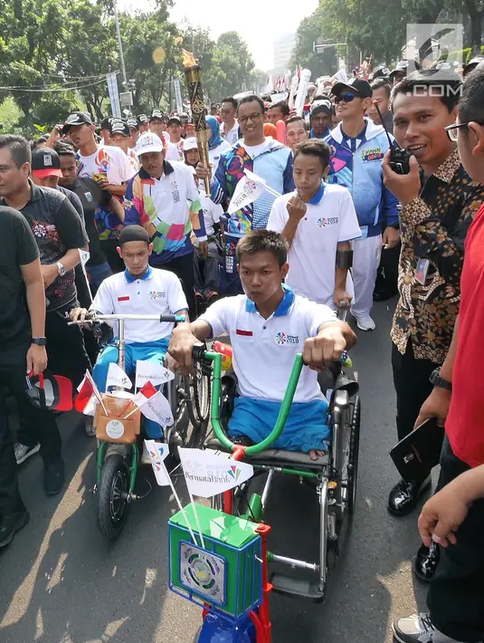 Gubernur DKI, Anies Baswedan membawa obor saat Pawai Obor Asian Para Games di Balai Kota DKI Jakarta, Minggu (30/9). Pawai obor dimulai dari Balai Kota dan berakhir di Gedung Kementerian Pemuda dan Olahraga (Kemenpora). (Liputan6.com/Herman Zakahria)