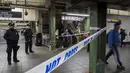 Penumpang melintasi aparat kepolisian yang berjaga di lorong stasiun kereta bawah tanah dekat lokasi teror bom pipa di New York City, Senin (11/12). Empat orang dikabarkan mengalami luka-luka akibat teror bom tersebut. (Drew Angerer/Getty Images/AFP)