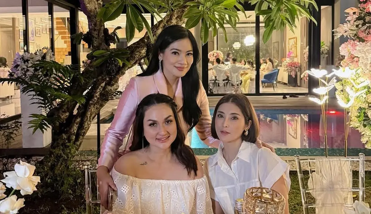 Eva Anindita memilih mengenakan atasan kemeja putih lengan pendek dengan aksen kantong depan. Melengkapi tampilan dengan anting-anting emas. [@tengkudewiputri_tdp]