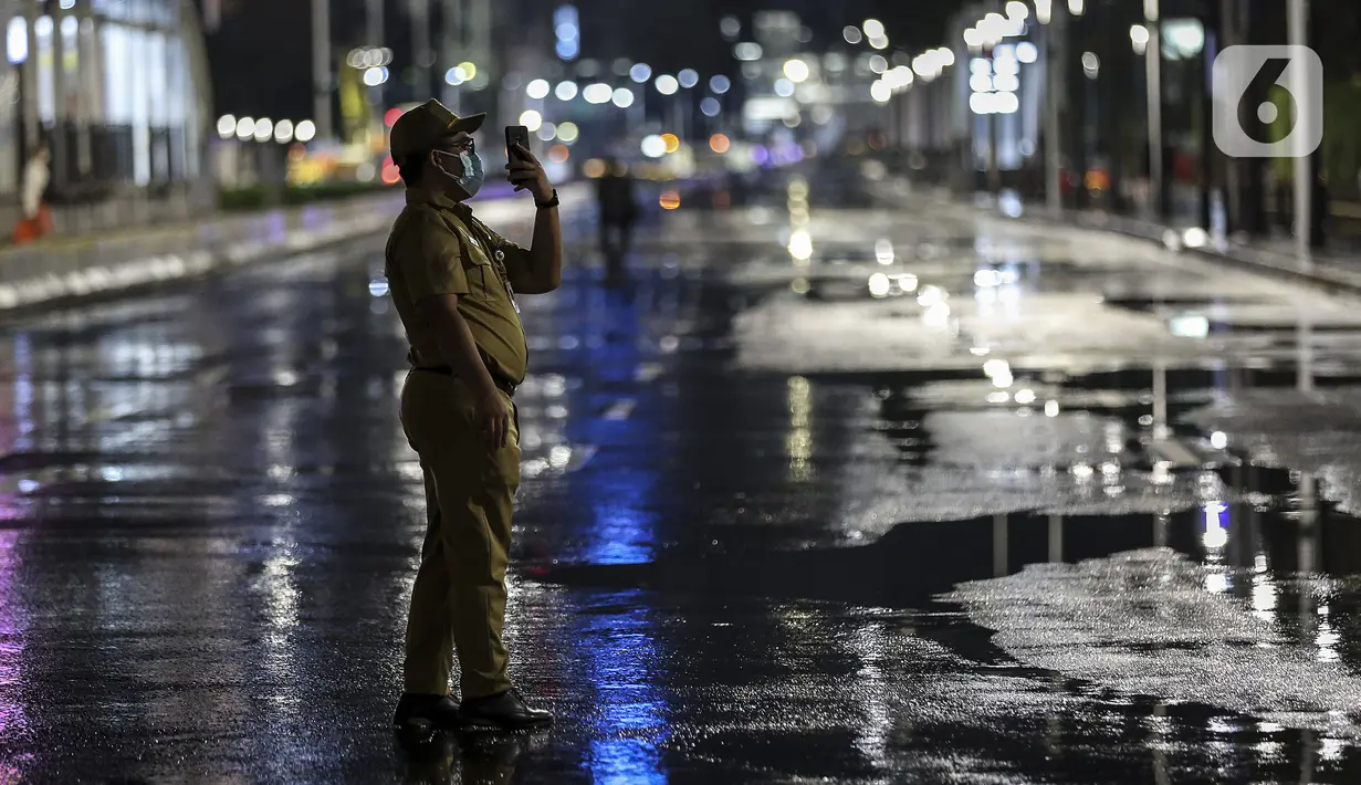 Seorang pria mengambil gambar saat diberlakukannya Car Free Night dan Crowd Free Night di Jalan Sudirman-MH Thamrin, Jakarta (31/12/2020). Jalan Sudirman-MH Thamrin ditutup pada malam pergantian tahun untuk mencegah kerumunan warga. (Liputan6.com/Johan Tallo)
