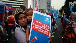 Seorang buruh membawa anak saat melakukan aksi di depan Kedutaan besar Jerman di Jakarta, Selasa (18/7). Mereka menuntut PT Panarub Dwikarya karena dinilai telah berlaku tidak adil pada buruh yang bekerja di perusahan tersebut. (Liputan6.com/Angga Yuniar)