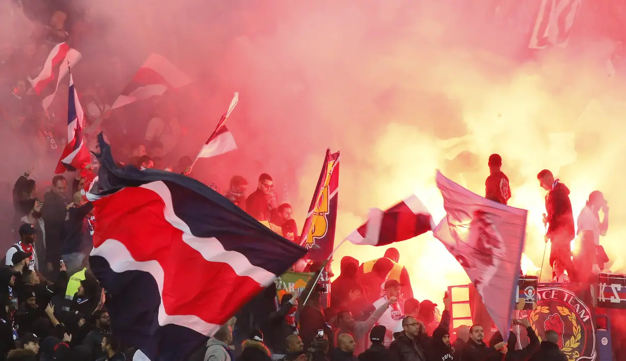 Para suporter PSG menyalakan flare merayakan kemenangan atas Nice pada laga Ligue 1 Prancis di Stadion Parc des Princes, Paris, Jumat (27/10/2017). PSG menang 3-0 atas Nice. (AFP/Michel Euler)