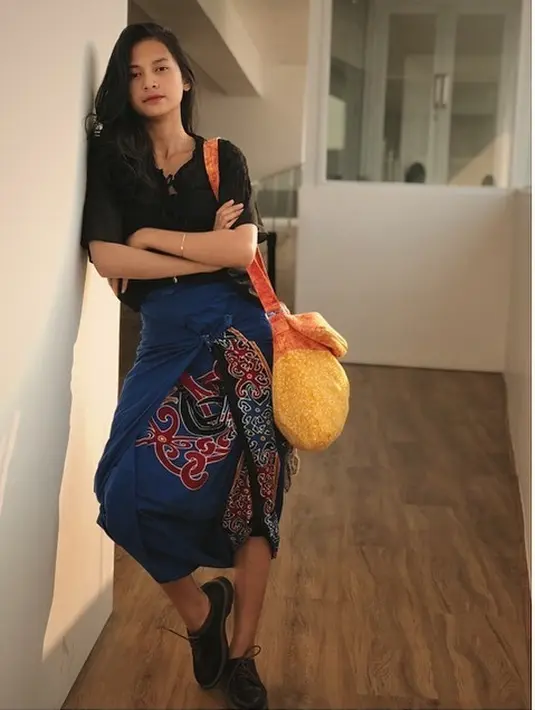 Penampilannya memang selalu tomboy, menggunakan baju hitam dengan rok berwarna biru bermotif batik, ia tampil santai dilengkapi sepatu berwarna hitam. Tas kuning yang disandangnya membuat penampilannya manis. (Liputan6.com/IG/@indahpermatas)
