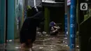 Warga melintasi banjir di kawasan Kebon Pala, Kampung Melayu, Jakarta Timur, Sabtu (16/7/2022). Karena rumahnya terendam banjir, sejumlah warga sudah mulai menyelamatkan barang-barang berharga ke tempat yang lebih tinggi. (merdeka.com/Imam Buhori)
