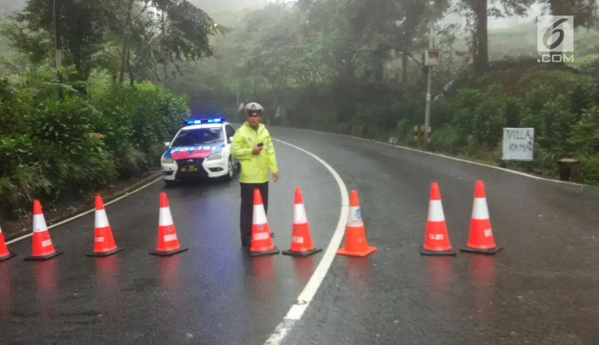 Polisi menutup jalan dan mengalihkan arus lalu lintas usai terjadi longsor di kawasan Puncak Bogor, Jawa Barat (6/2). Menurut pihak kepolisian setempat titik longsor saat ini bertambah dari empat menjadi enam lokasi. (Liputan6.com/Pool/Polres Bogor)