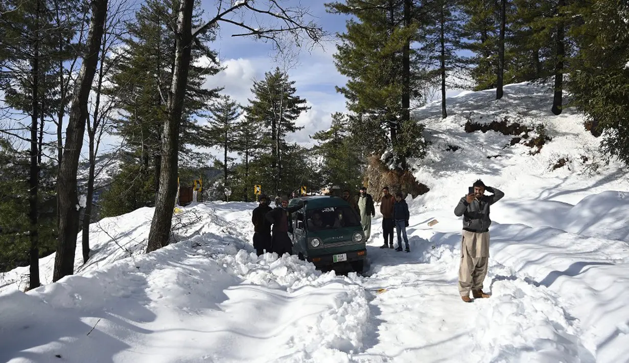 Wisatawan lokal yang terdampar menunggu di sepanjang jalan Bukit Murree, Pakistan, 9 Januari 2022. Sebanyak 22 wisatawan tewas saat sekitar 1.000 kendaraan terjebak salju tebal di Bukit Murree. (Aamir QURESHI/AFP)
