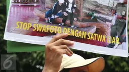 Peserta aksi dari Yayasan Scorpion Indonesia menunjukan poster saat menggelar aksinya di depan Kementrian Lingkungan Hidup dan Kehutan (KLHK), Jakarta, Senin (20/3). (Liputan6.com/Angga Yuniar)