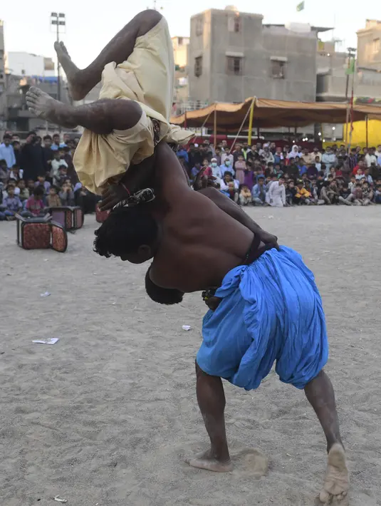 Peserta berusaha menjatuhkan lawannya saat turnamen gulat tradisional Sindhi Malakhra di kota pelabuhan Karachi, Pakistan pada Minggu (13/12/2020). Gulat kuno yang dimulai sejak 5.000 tahun lalu ini salah satu olahraga favorit di kalangan pria. (Photo by Asif HASSAN / AFP)