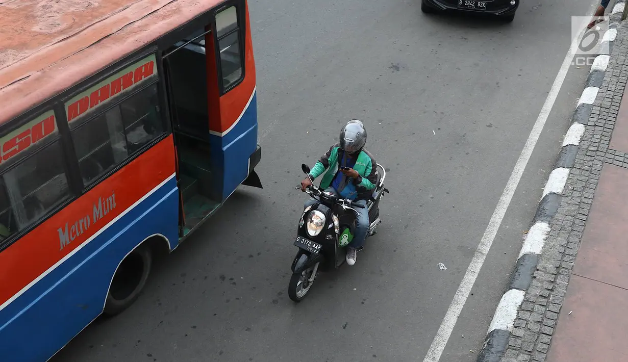 Pengendara sepeda motor mengoperasikan gawainya saat berkendara di Jakarta, Jumat (8/2). Polisi akan melakukan tindakan hukum berupa tilang kepada pengendara yang menggunakan GPS saat berkendara. (Liputan6.com/Immanuel Antonius)