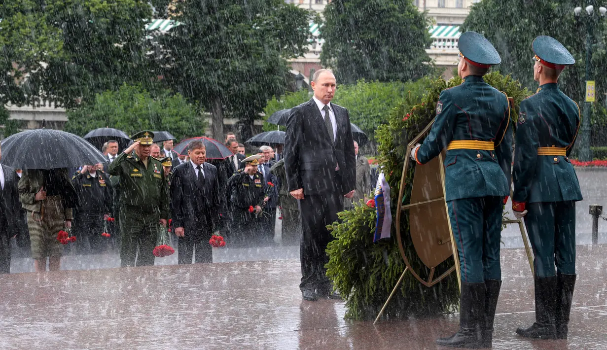 Presiden Rusia Vladimir Putin berdiri di tengah hujan selama upacara kehormatan untuk memperingati invasi Nazi Jerman pada 1941 di Benteng Kremlin, di Moskow, Kamis (22/6). (Alexei Druzhinin/Sputnik, Kremlin Pool Photo via AP)