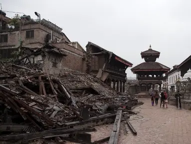 Pejalan kaki melintas di sisi salah satu bangunan bersejarah yang hancur akibat gempa berkekuatan 7,8  di sekitar Kathmandu, Nepal  (30/4/2015). Gempa berkekuatan 7,8 yang meluluhlantakkan Nepal pada 25 April 2015 lalu. (Nicolas Asfouri/AFP)