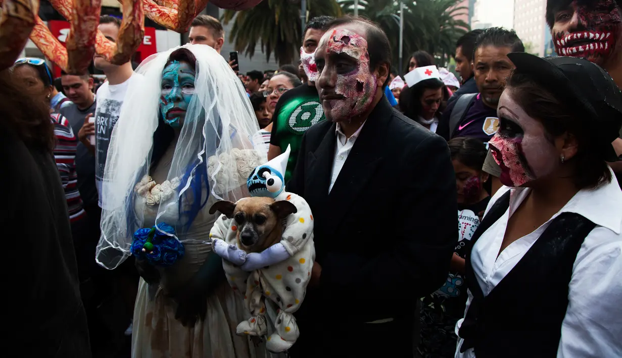 Beberapa orang berjalan selama Zombie Walk di Mexico City, Minggu (11/11). Ratusan orang dengan penampilan yang seram serta mengenakan pakaian compang-camping berkumpul di pusat bersejarah ibu kota Meksiko dalam acara tahunan tersebut. (AP/Claudio Cruz)