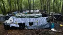Para migran berjalan di antara tenda-tenda yang dibuat seadanya di kamp darurat di hutan di luar Velika Kladusa, Bosnia pada 25 September 2020. Bosnia menjadi salah satu tempat singgah para imigran dan pengungsi dalam perjalanannya ke Eropa Barat. (AP Photo/Kemal Softic)