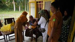 Tenaga kesehatan Siti Nurjanah (kiri) dibantu rekan-rekannya memberikan vaksin campak kepada seorang anak dalam kampanye vaksinasi campak dari rumah ke rumah menyusul wabah di Sumenep, Pulau Madura, Jawa Timur, Senin 8 September 2025. (AP Photo/Dita Alangkara)