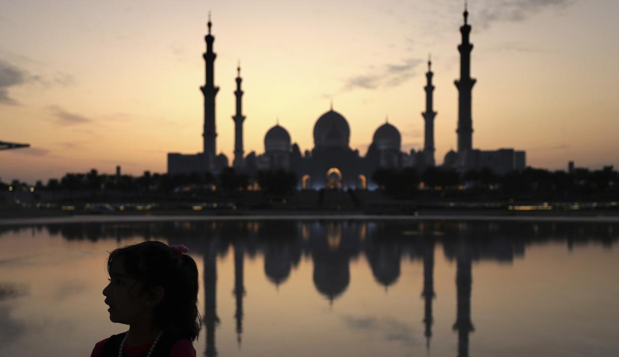 Seorang gadis bermain di depan sebuah kolam saat matahari terbenam di belakang Masjid Agung Sheikh Zayed di Abu Dhabi, Uni Emirat Arab (8/11/2019). asjid ini dibangun oleh presiden pertama Uni Emirat Arab, yaitu Sheikh Zayed bin Sultan Al Nahyan. (AFP Photo/Kamran Jebreili)