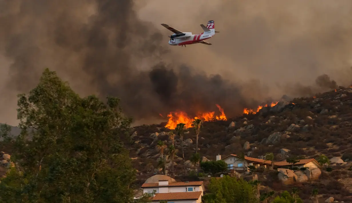 Sebuah tangki udara bersiap untuk menjatuhkan retardant pada kebakaran hutan yang membakar dekat rumah-rumah di lereng bukit, Selasa (6/9/2022), dekat Hemet, California. Pada Selasa malam api telah membakar 4.500 hektar dan 5% terkandung, menurut tweet dari Cal Fire. (AP Photo/Ringo H.W. Chiu)