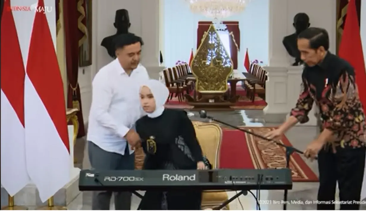 Namun, mic yang akan digunakan Putri tersenggol hingga hampir jatuh. Presiden Jokowi dengan sigap membantu Putri Ariana memperbaiki posisi mic dengan benar. [Youtube/Sekretariat Presiden]