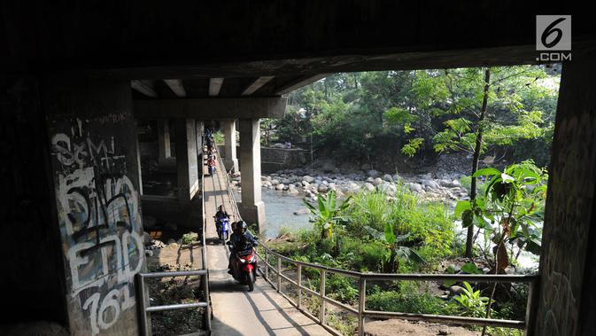 Pengendara motor melewati jembatan Ciliwung yang berada di bawah tol ruas Gadog, Ciawi, Bogor (16/68). Jembatan ini menjadi jalan alternatif bagi pemotor untuk menghindari kemacetan lalu lintas. (Merdeka.com/Arie Basuki)