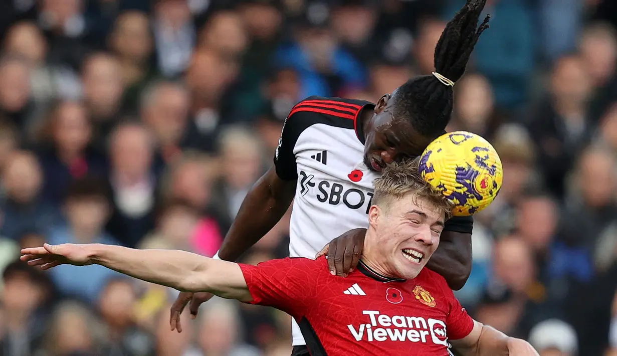 Pemain MU, Rasmus Hojlund (kanan), kalah bersaing dengan pemain Fulham, Calvin Bassey, saat berebut bola di udara dalam pekan ke-11 Premier League 2023/2024 yang berlangsung di Stadion Craven Cottage, London, Sabtu (4/11/2023) malam WIB. (AFP/Adrian Dennis)