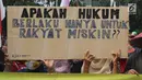 Warga Pulau Pari membawa papan bertuliskan tuntutan saat menggelar aksi di depan PN Jakarta Utara, Kamis (12/7). Mereka menolak dugaan kriminalisasi terhadap Ketua RW Pulau Pari Sulaiman dalam kasus penyerobotan lahan. (Liputan6.com/Arya Manggala)