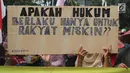 Warga Pulau Pari membawa papan bertuliskan tuntutan saat menggelar aksi di depan PN Jakarta Utara, Kamis (12/7). Mereka menolak dugaan kriminalisasi terhadap Ketua RW Pulau Pari Sulaiman dalam kasus penyerobotan lahan. (Liputan6.com/Arya Manggala)
