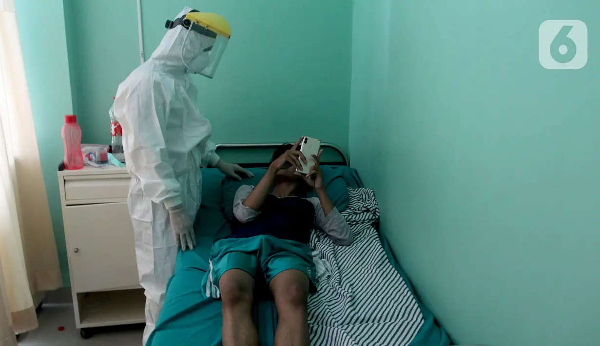 Paramedis mengecek kesehatan pasien positif COVID-19 yang dirawat di Puskesmas Jurumudi, Tangerang, Banten, Kamis (17/2/2022). Kasus positif COVID-19 di Kota Tangerang terus mengalami penurunan kasus dari 2000 kasus perhari menjadi 1000 kasus perhari. (merdeka.com/Arie Basuki)
