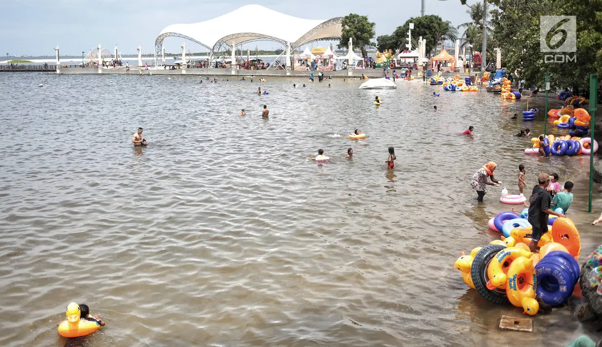 Sejumlah pengunjung bermain air di Beach Pool Ancol, Jakarta, Selasa (25/12). Pasangnya air laut dan cuaca buruk mengakibatkan pantai Ancol sepi pengunjung saat libur Natal 2018. (Liputan6.com/Faizal Fanani)