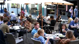 Pelanggan menikmati makan siang di meja di luar restoran di Soho, London, ketika pemerintah Inggris mempertimbangkan pembatasan baru pada Minggu (20/9/2020). Inggris kemungkinan akan kembali memberlakukan tindakan lockdown akibat lonjakan tajam infeksi virus corona COVID-19. (DANIEL LEAL-OLIVAS/AFP)