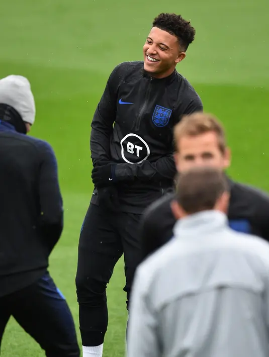 Gelandang Inggris, Jadon Sancho tertawa saat mengikuti sesi pelatihan tim  di Staplewood Campus di southampton, Inggris selatan (9/9/2019). Inggris akan bertanding melawan Kosovo pada grup A Kualifikasi Euro 2020 di Stadion Saint Mary. (AFP Photo/Glyn Kirk)