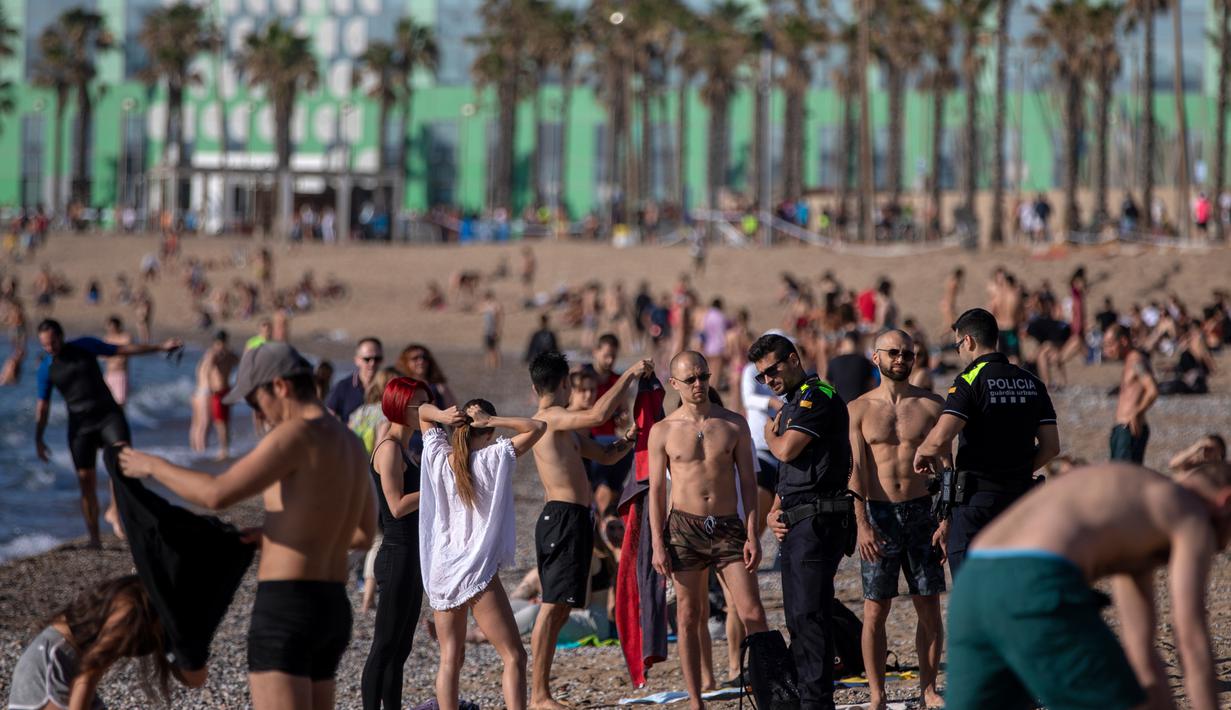 Petugas polisi meminta orang-orang untuk tidak duduk sambil berpatroli di pantai di Barcelona, Spanyol, Rabu, (20/5/2020). Berjemur dan berenang masih tidak diizinkan di pantai tersebut.  (AP Photo/Emilio Morenatti)