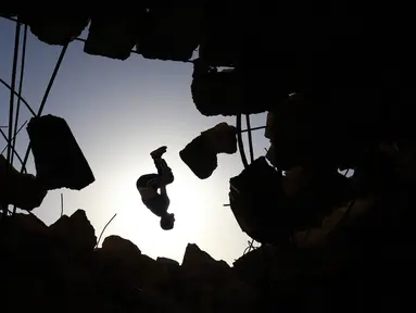 Seorang pemuda Suriah melakukan parkour di atas reruntuhan bangunan yang hancur akibat serangan pasukan rezim di kota Binnish di provinsi barat laut Idlib pada 17 Juni 2020. Parkour merupakan olahraga ketangkasan yang terdiri dari lari, melompat, salto dan berayun. (Abdulaziz KETAZ / AFP)