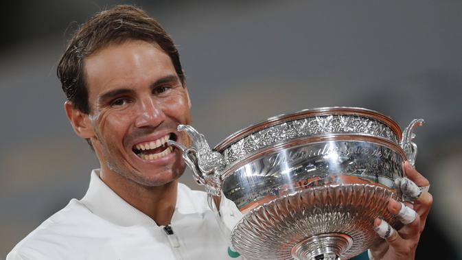 RAFAEL NADAL JUARA PRANCIS TERBUKA 2020: Petenis Rafael Nadal menggigit trofi saat merayakan kemenangannya atas Novak Djokovic pada final Prancis Terbuka 2020 di Stadion Roland Garros, Paris, Minggu (11/10/2020). Nadal menyamai rekor Roger Federer dengan 20 gelar Grand Slam. (AP Photo/Michel Euler)