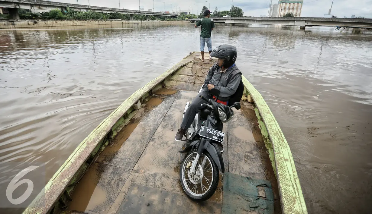 Seorang pemotor menggunakan jasa perahu eretan saat menyeberangi Kanal Banjir Barat (KBB) ), Teluk Gong, Jakarta, Rabu (10/2/2016). Dengan tarif Rp 2000, mereka dapat mempersingkat jarak dan waktu dari Teluk Gong menuju Pluit. (Liputan6.com/Faizal Fanani)