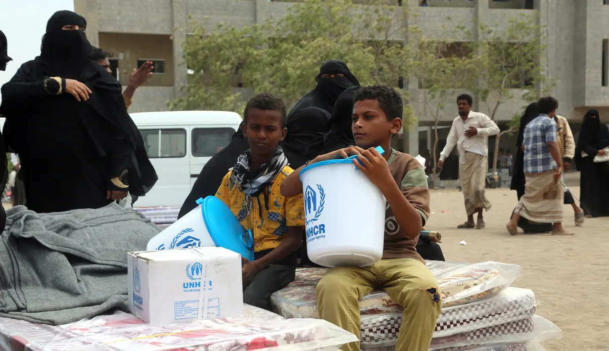 Dua bocah menerima bantuan yang diberikan oleh Komisaris Tinggi PBB untuk Pengungsi (UNHCR) di kota Hodeidah, Yaman (11/4). Perang di Yaman telah menewaskan lebih dari 10 ribu orang dan membuat lebih dari dua juta orang mengungsi. (AFP Photo/Abdo Hyder)