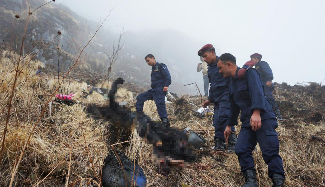 Petugas memeriksa jasad tubuh yang terbakar di dekat jatuhnya pesawat Twin Otter milik maskapai Tara Air di pegunungan Nepal, Rabu (24/2). Di sekitar puing pesawat juga ditemukan potongan tubuh yang diduga milik para penumpang. (REUTERS/Santosh Gautam)